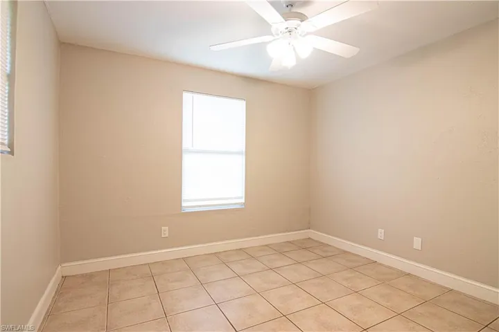 Empty room with light tile patterned floors and ceiling fan