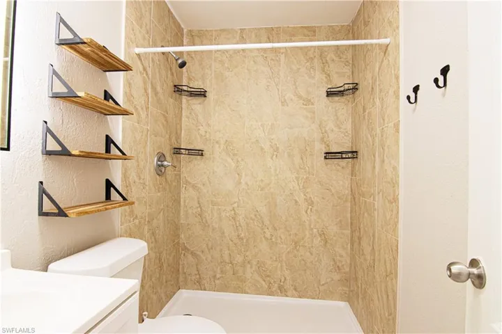 Full bathroom with vanity, a textured wall, and a stall shower