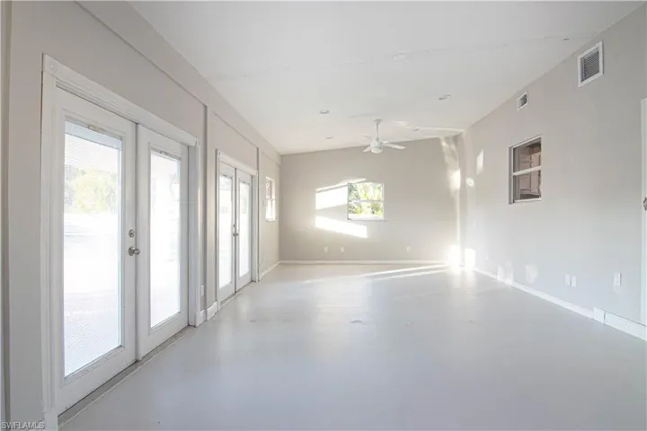 Empty room with french doors, finished concrete floors, and a ceiling fan