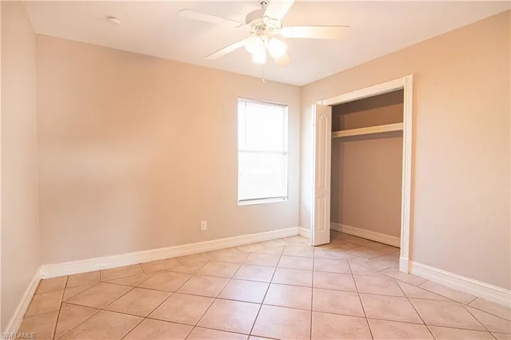 Unfurnished bedroom with a ceiling fan, light tile patterned flooring, and a closet