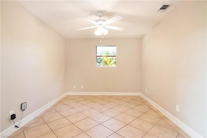 Empty room with light tile patterned floors and ceiling fan