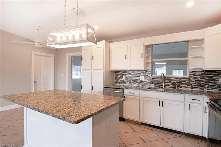 Kitchen featuring open shelves, white cabinetry, light stone counters, a kitchen island, and recessed lighting