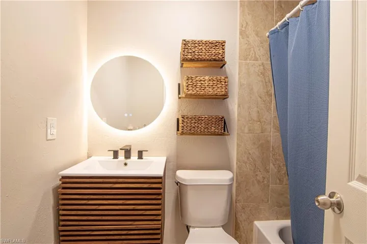 Bathroom with vanity, a textured wall, and shower / tub combo