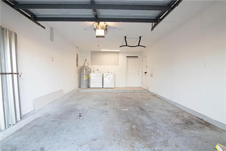 Garage featuring washer and clothes dryer and water heater