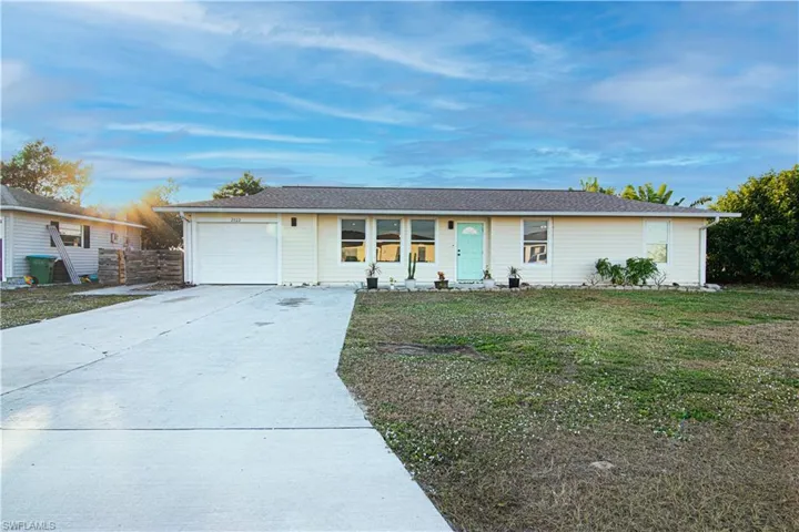 Ranch-style home with a front yard, concrete driveway, and a garage