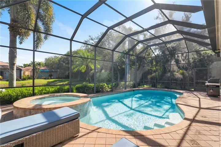 View of swimming pool featuring a patio, a grill, an in ground hot tub, a lanai, and pool water feature
