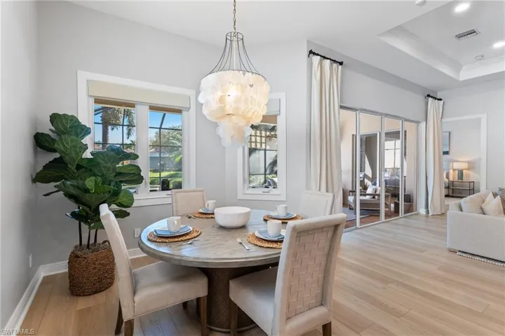 Breakfast area with a notable chandelier, a raised ceiling and lots of windows
