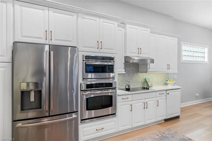 Kitchen featuring tasteful backsplash, stainless steel appliances, white cabinets and custom beverage cooler