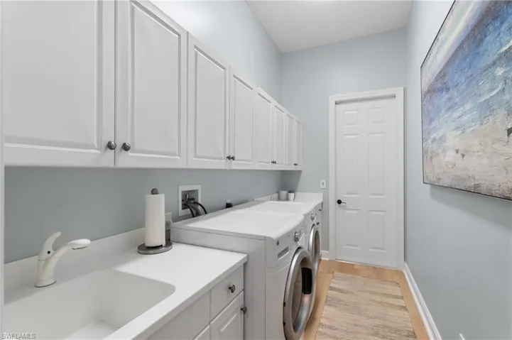 Washroom featuring cabinets, sink, washing machine and dryer with entry to the garage