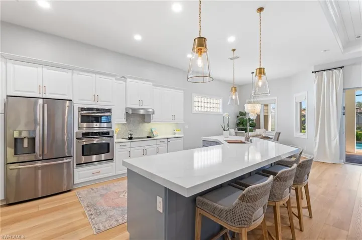 Kitchen with stainless steel appliances, an island with sink, with white & soft blue cabinetry