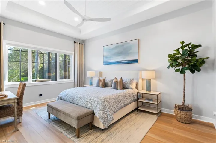 Primary Bedroom with hardwood / wood-style flooring, ceiling fan, and a tray ceiling