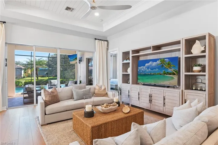 Living room featuring light hardwood / wood-style flooring, wooden ceiling, ornamental molding, a raised ceiling, and ceiling fan