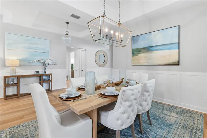 Dining Room with decorative wall panels, chandelier and a tray ceiling