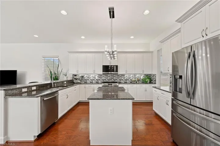 Kitchen featuring white cabinetry, stainless steel appliances, and decorative light fixtures