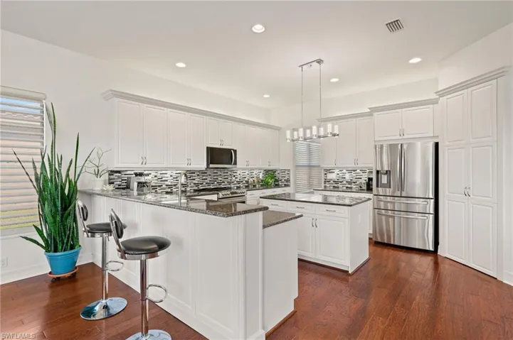 Kitchen featuring white cabinetry, appliances with stainless steel finishes, pendant lighting, and kitchen peninsula