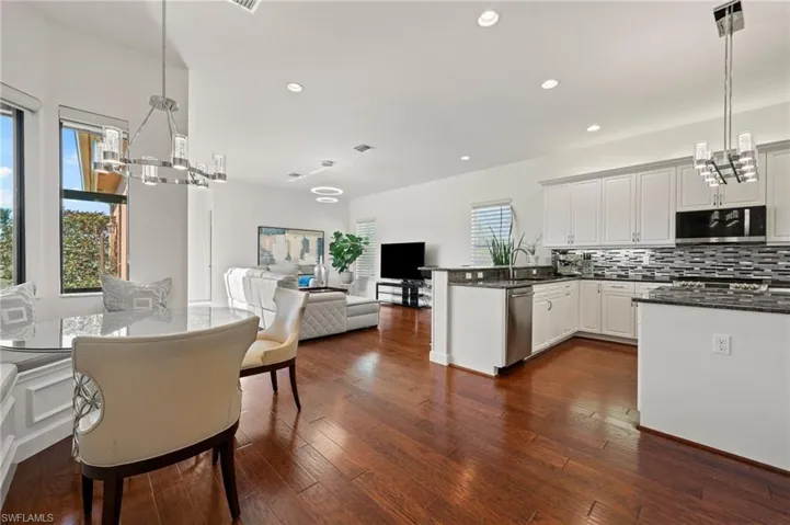 Kitchen featuring white cabinetry, appliances with stainless steel finishes, decorative light fixtures, and decorative backsplash