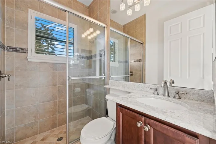 Bathroom featuring walk in shower, vanity, and toilet