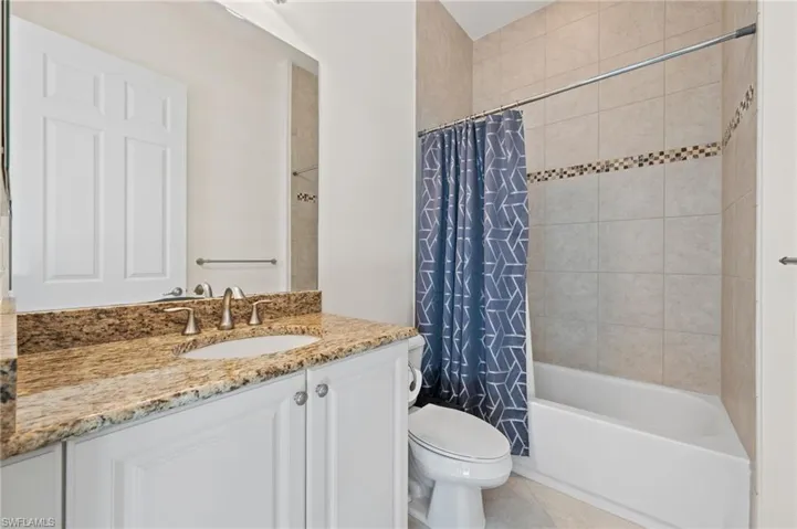 Full bathroom featuring shower / bathtub combination with curtain, vanity, tile patterned floors, and toilet