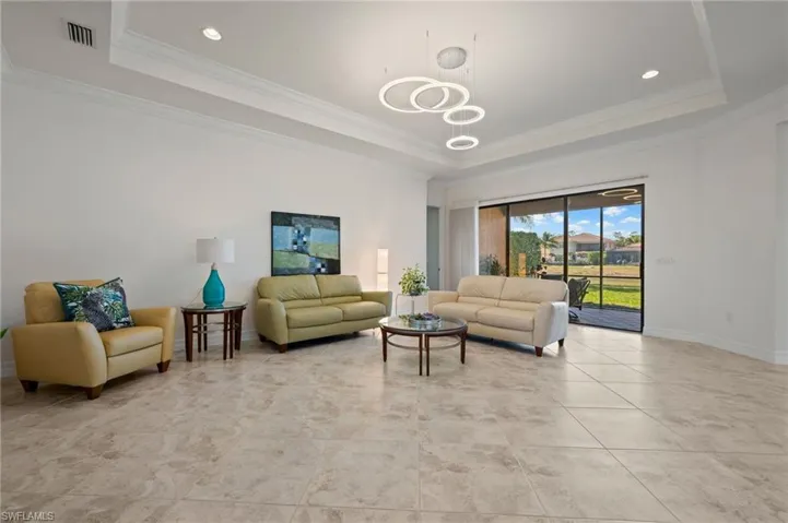Living room featuring crown molding, a chandelier, and a tray ceiling
