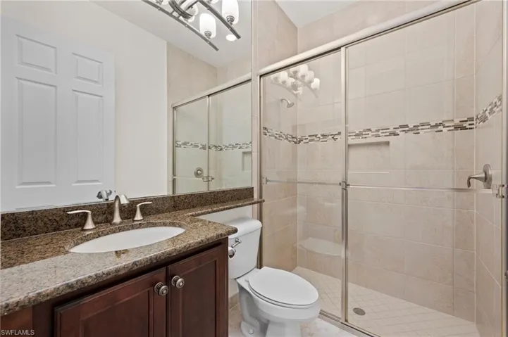 Bathroom with vanity, a shower with door, and toilet