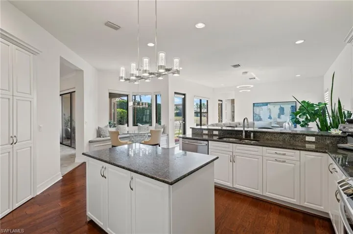 Kitchen with sink, decorative light fixtures, dark stone countertops, dishwasher, and white cabinets