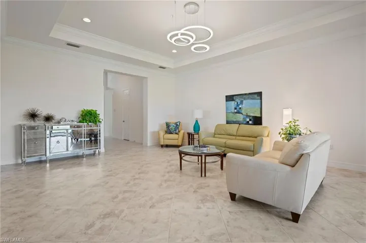 Living room featuring crown molding, a tray ceiling, and a chandelier