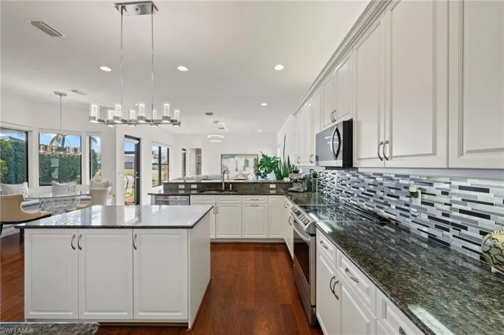 Kitchen featuring pendant lighting, sink, white cabinets, and appliances with stainless steel finishes