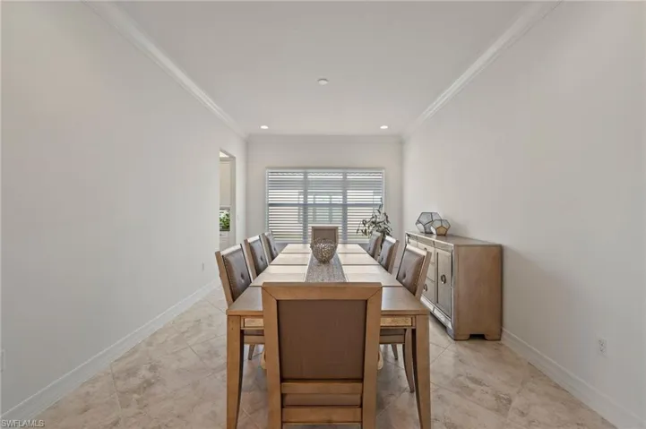 Dining area with light tile patterned flooring and ornamental molding