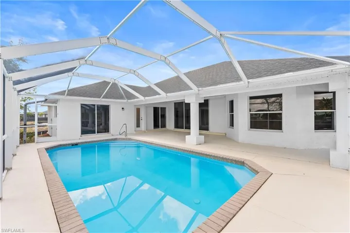 Swimming pool featuring glass enclosure, a patio, and a sunroom