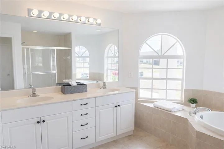 Full bathroom with a bath, double vanity, light tile patterned floors, and a shower stall