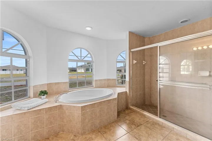 Full bath featuring a shower stall, a garden tub, and light tile patterned flooring