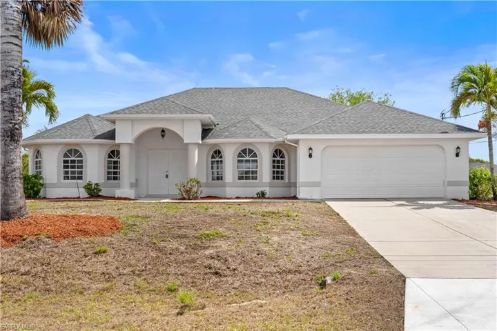 View of front facade with stucco siding, an attached garage, roof with shingles, and driveway