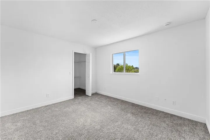 Unfurnished bedroom with light carpet and a spacious closet