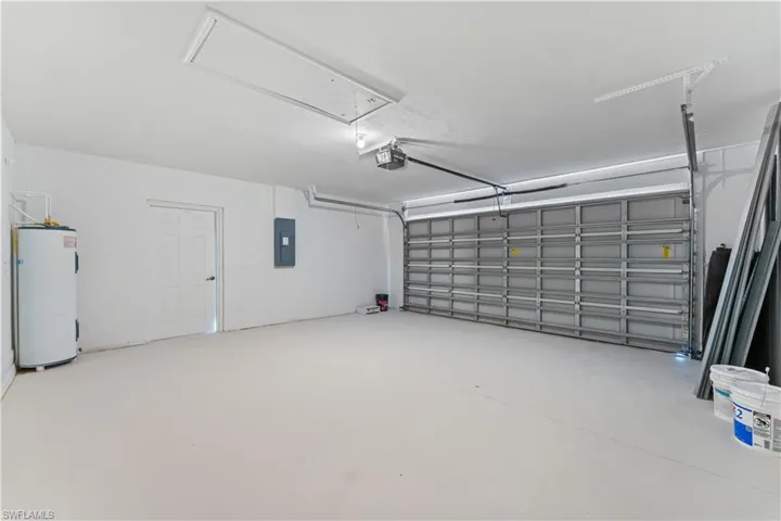 Garage featuring water heater, electric panel, and a garage door opener