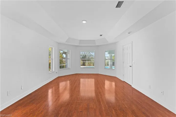 Unfurnished room with a tray ceiling and dark wood finished floors