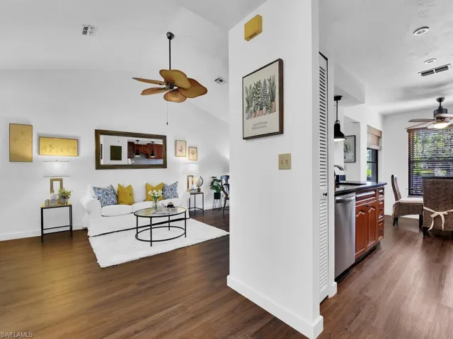 Living room featuring lofted ceiling, sink, dark hardwood / wood-style floors, and ceiling fan