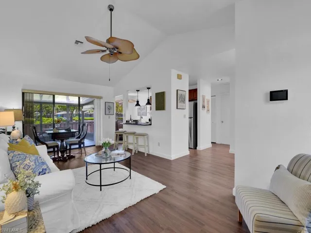 Living room featuring high vaulted ceiling, ceiling fan, and dark hardwood / wood-style floors