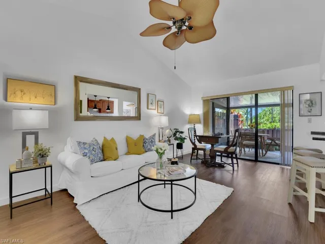 Living room featuring high vaulted ceiling, ceiling fan, and hardwood / wood-style flooring