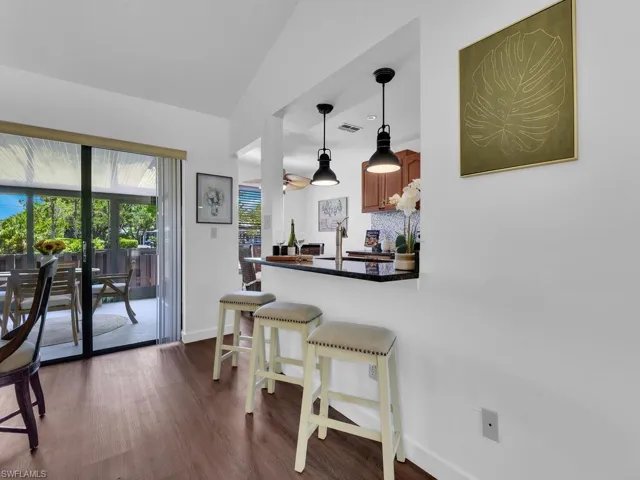 Kitchen featuring kitchen peninsula, lofted ceiling, dark hardwood / wood-style flooring, hanging light fixtures, and a breakfast bar area