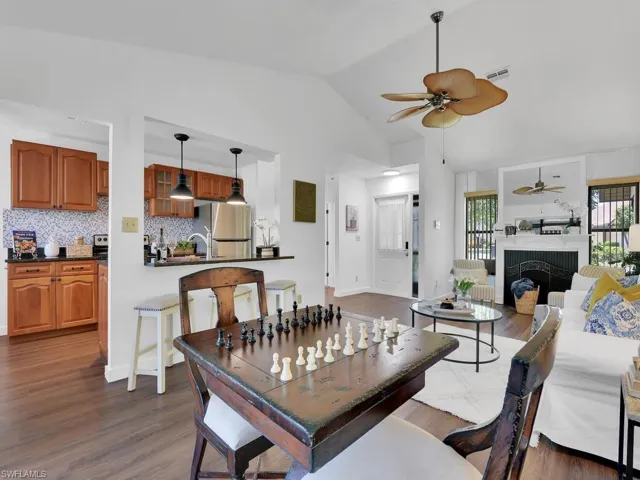 Dining space with high vaulted ceiling, dark wood-type flooring, ceiling fan, and a fireplace