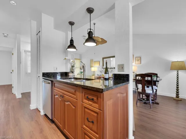 Kitchen featuring decorative light fixtures, sink, dishwasher, and hardwood / wood-style floors