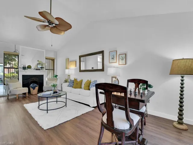 Living room featuring high vaulted ceiling, hardwood / wood-style flooring, a tile fireplace, and ceiling fan