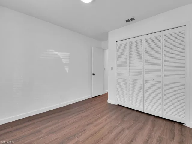 Unfurnished bedroom with a closet and dark wood-type flooring