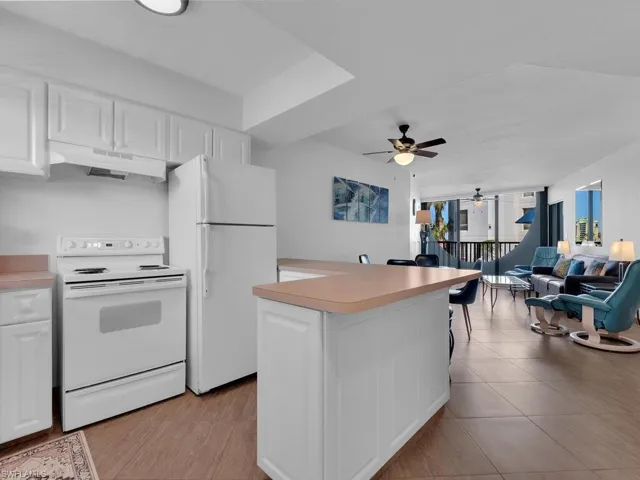 Kitchen with white cabinets, light tile patterned floors, white appliances, and ceiling fan