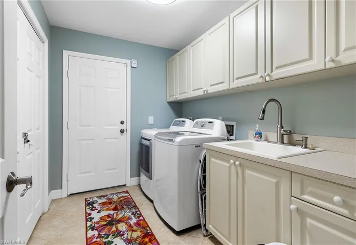 Laundry area with cabinet space, washer and dryer, and light tile patterned floors
