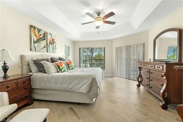 Bedroom with wood finish floors, a ceiling fan, and a tray ceiling