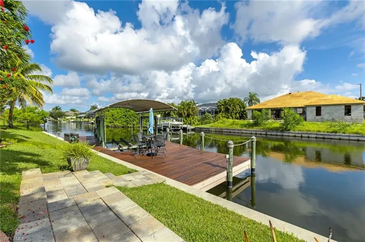 Dock area with boat lift, a water view, and a lawn