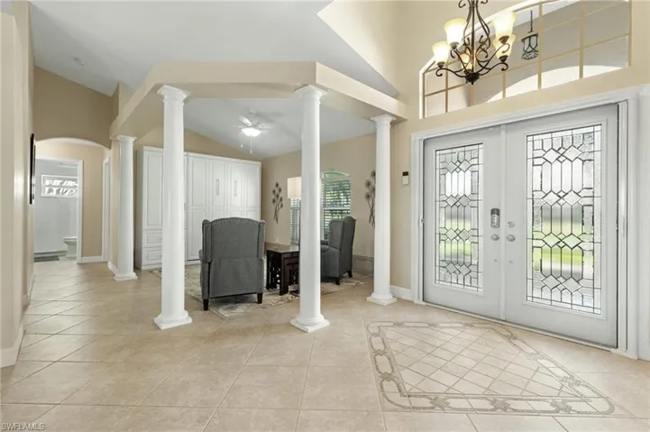 Foyer with ceiling fan, light tile patterned floors, vaulted ceiling, and arched walkways