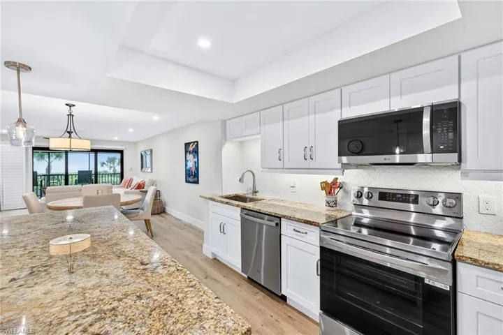 Kitchen with stainless steel appliances, light stone countertops, white cabinetry, light wood-type flooring, and recessed lighting