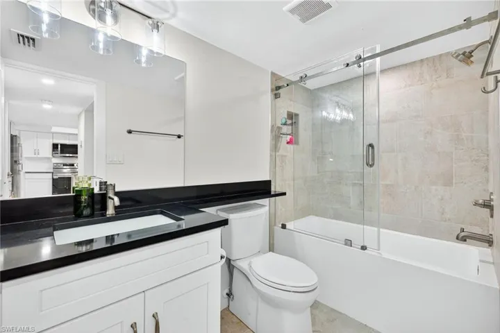 Bathroom with shower / bath combination with glass door and vanity